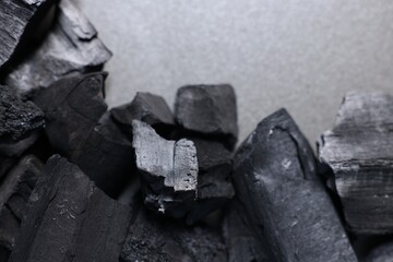 Pieces of black coals on grey table, top view