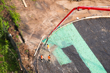 Aerial view of construction workers pouring concrete foundation with a red concrete pump. Civil engineering and modern construction site