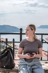 Fototapeta premium Woman enjoys solo travel, retreat and mindfulness sea, mountain, coast, marina; exploring slow adventure, freedom, calm, awareness, soft experience, relaxation, selfcare, youth lifestyle.