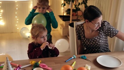 Family Fun Children Joyfully Blowing Up Balloons. Kids inflating balloons, prepare for birthday party. 3,6, 14 years old siblings racing blowing balloon, decorate the room. Bonding time together. Joy