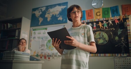 Renewable Energy Lesson: Elementary School Boy Holding Notebook Speaking, Giving Presentation on...