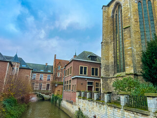  Gothic church and historic town houses in Leuven with canal under blue sky