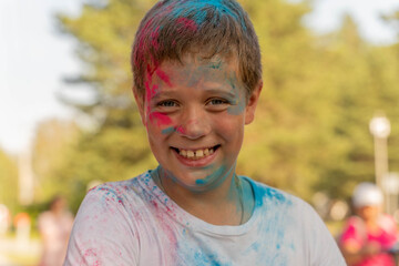 Boy smiling with colorful powder on his face and shirt at holi festival