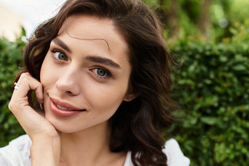 Young woman with wavy brown hair enjoying a sunny summer day in the park