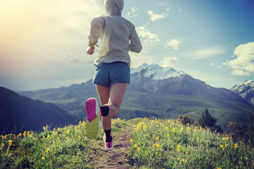 Trail runner running on the high altitude grassland mountain top trail