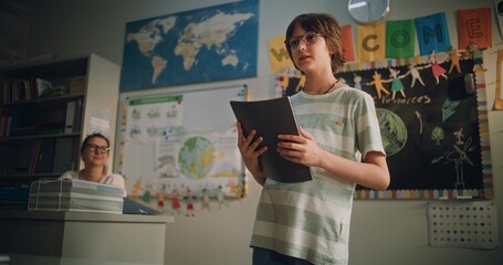 Renewable Energy Lesson: Elementary School Boy Holding Notebook Speaking, Giving Presentation on...