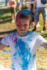 Boy smiling with colorful powder on his face and clothes at holi festival
