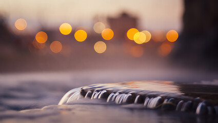 Water flowing over rocks with bokeh lights image