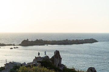 People standing on rocks overlooking the ocean