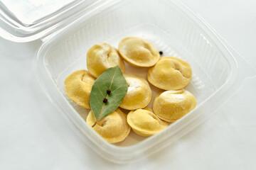 Deliciously Prepared Traditional Dumplings Featuring Fresh Ingredients and Aromatic Bay Leaves in a Clear Takeout Container