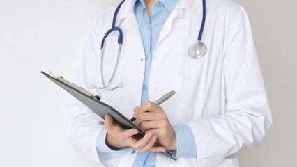 Close up of doctor woman wearing stethoscope and white coat over blue blouse is standing and...