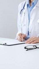 Unknown female doctor completing healthcare paperwork, clipboard positioned near laptop and...