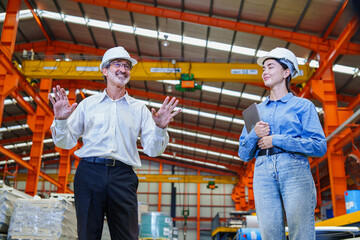 Senior engineer giving team briefing inside metal roofing factory, with workers listening...