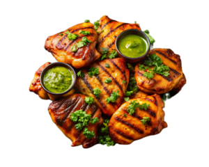 Close up of grilled chicken pieces with green sauce and parsley on a black background