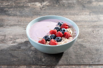 Healthy smoothie bowl with berries on wooden table