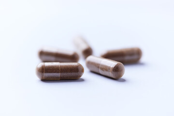 Ashwagandha (Withania somnifera) capsules. Concept for a healthy dietary supplementation. Bright paper background. Close up. Copy space.	