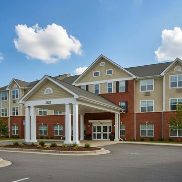 new homes in the netherlands, Senior retirement community with apartment-style living. Large brick hotel building with brown roof and white windows. Tree-lined street and parking lot outside.