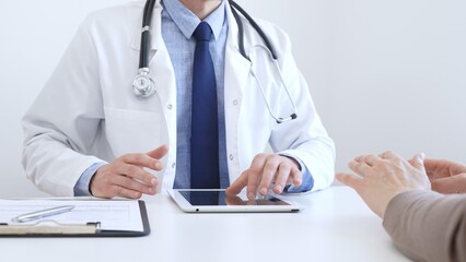 Doctor man showing information on tablet to patient woman during medical visit, explaining...