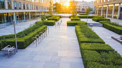 Modern urban courtyard at sunset with greenery and bicycle racks