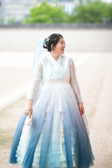 In Seoul in June 2025, two Korean women in their twenties wearing pink and sky-blue hanbok stand in...