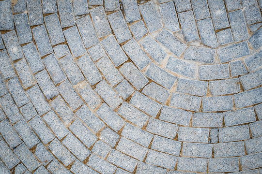 Cobblestone pavement forming a semicircle with gray bricks. Architecture details