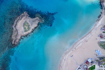 Drone aerial view of tropical beach with turquoise water and remote island.