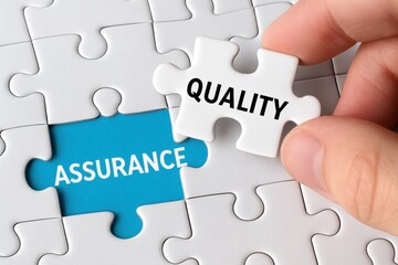 Fototapeta premium Quality Assurance puzzle: A hand places a puzzle piece labeled Quality into a partially assembled puzzle, emphasizing the concept of quality assurance and its importance in problem-solving.