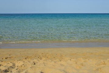 Crystal clear water gently lapping on golden sandy beach on sunny day