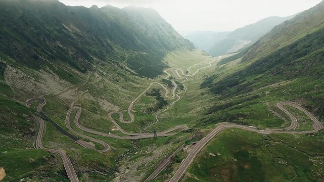 Stunning 4K aerial footage of the famous Transfăgărășan road snaking through the Carpathian Mountains in Romania. Captured from a drone, the video showcases the dramatic curves, lush green forests, an