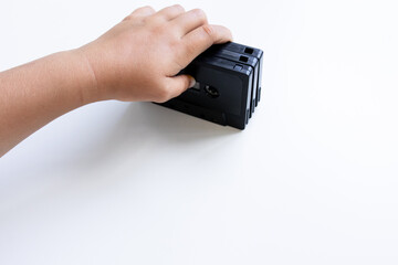 Child hand holding vintage vhs tape on white background
