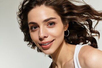 Beautiful young woman poses gracefully in studio with chic makeup and flowing hair