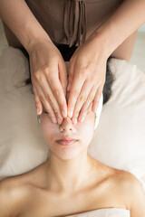 beautician covering client's face with warm towel before facial in aesthetic clinic medium shot