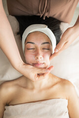 woman lying relaxed with eyes closed during facial treatment in aesthetic clinic medium shot