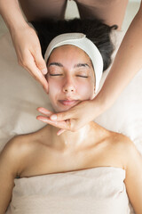 beautician placing warm towel on woman face before skincare treatment concept