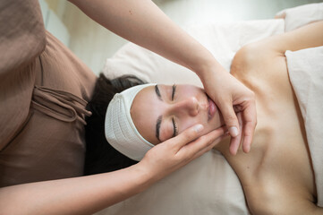 facial therapist massaging woman cheekbones in beauty studio skincare treatment concept