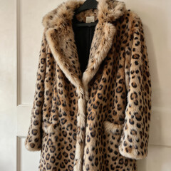 Luxurious faux fur coat iconic leopard print design. Plush, soft material with spotted pattern, contrasting light fur trim. Features include pockets, classic collar. Perfect for adding bold, chic