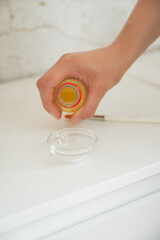 esthetician pouring yellow serum into glass bowl skincare treatment concept