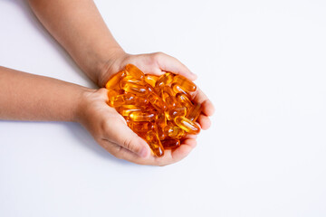 Child hands holding omega 3 fish oil capsules on white background
