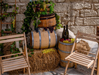 Barrels of wine next to chairs on the street.