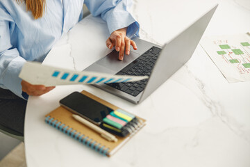 A focused individual analyzes color swatches while working on a laptop in a creative, innovative...