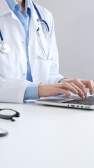 Doctor woman is typing on a laptop with a stethoscope, medical record, and pen on the desk in a...