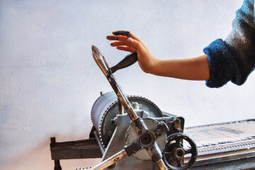 Artist hand operating manual printing press in traditional print studio. Printmaker ink stained...