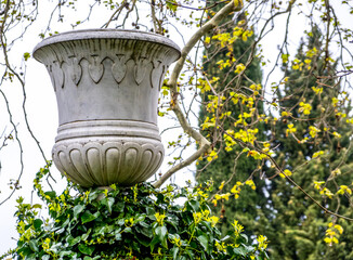 An ancient stone vase on a pedestal among plants.