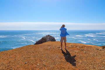 man standing at atlantic coast and takes photo with mobile photo camera, Algarve Portugal