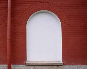A white arched niche in a brick wall.