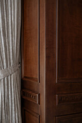 Detail of classic dark wood wall paneling next to an elegant, heavy curtain. A luxurious and...