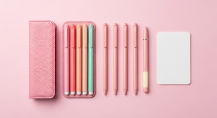 A collection of pink pens and a pink pen case are neatly arranged with a blank white card on a pink background