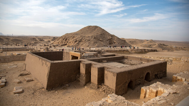 Ancient Egyptian mastaba tomb in Saqqara Necropolis with the Pyramid of Unas visible in the background.