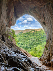 Scenic mountain view from the Thor's Cave entrance. Limestone cave, forest and white clouds. Peak...