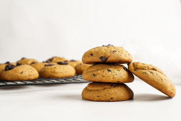 Stack of homemade cookies with chocolate chunks on white backdrop, close up and minimal style.